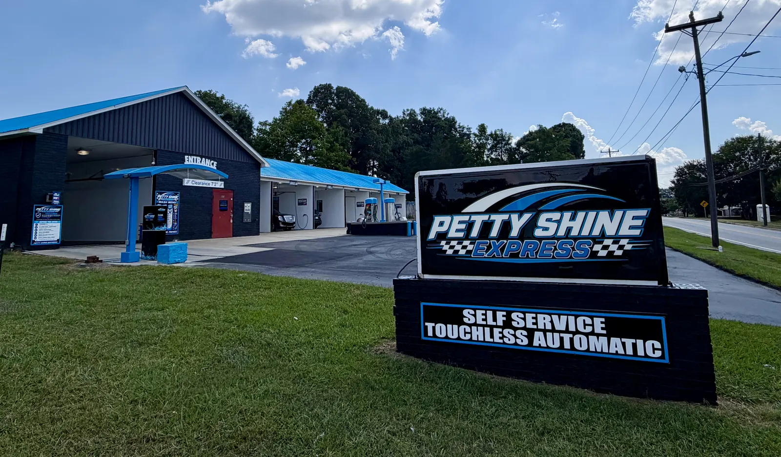 Petty Shine Express roadside sign reading self service and touchless automatic, with the wash building and bays behind it